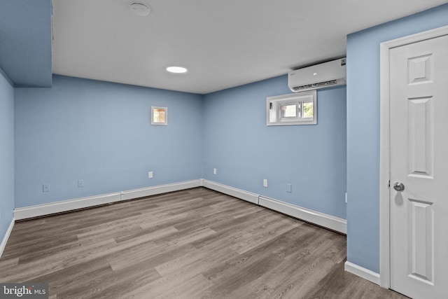 basement featuring a wall mounted AC, wood finished floors, and baseboards