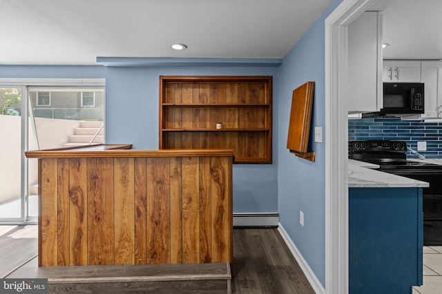 bar with black appliances, a baseboard heating unit, backsplash, wood finished floors, and baseboards