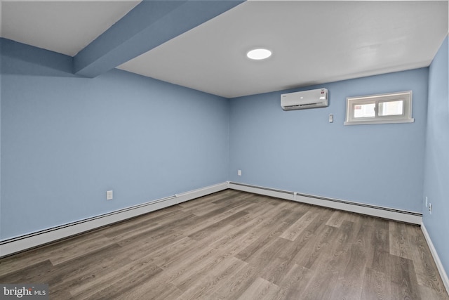 below grade area with an AC wall unit, baseboard heating, wood finished floors, and baseboards