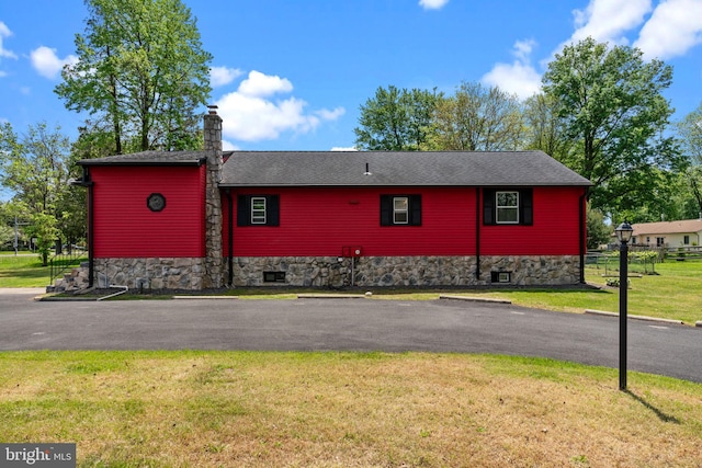 view of side of property with a chimney, stone siding, and roof with shingles