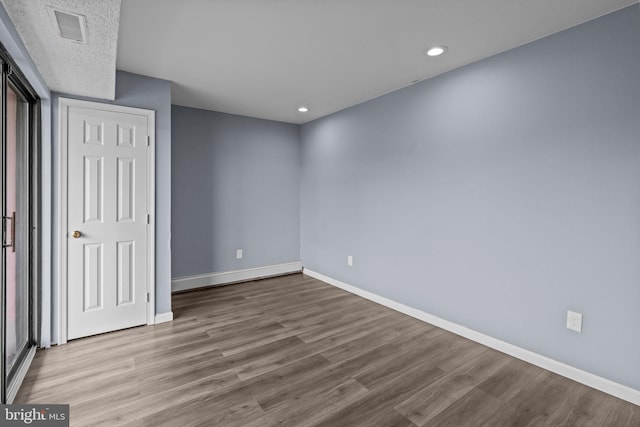 unfurnished bedroom with wood finished floors, baseboards, recessed lighting, and a baseboard radiator