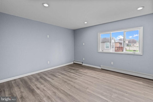 spare room featuring baseboard heating, wood finished floors, baseboards, and recessed lighting