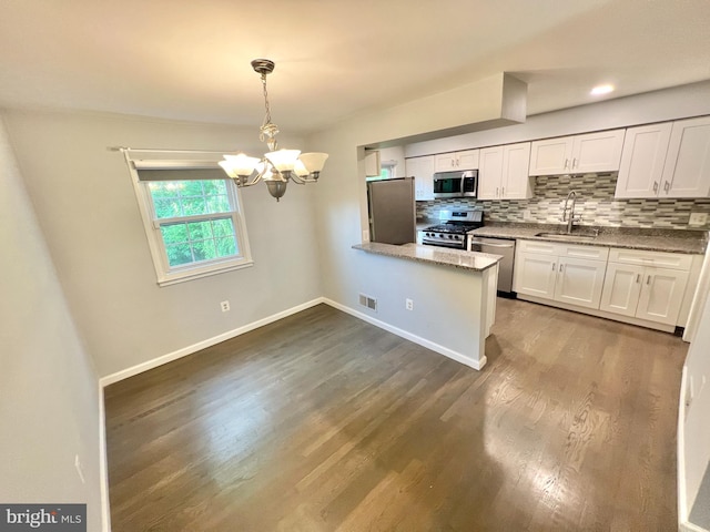 kitchen featuring a sink, stainless steel appliances, a chandelier, backsplash, and a peninsula