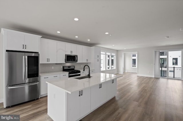kitchen featuring stainless steel appliances, a sink, white cabinets, light wood-style floors, and recessed lighting