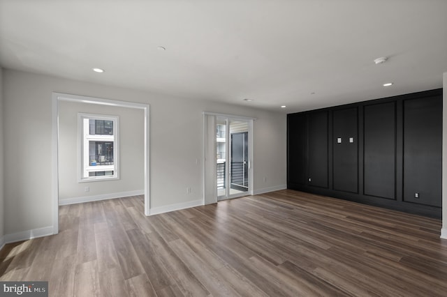 unfurnished bedroom featuring access to outside, wood finished floors, baseboards, and recessed lighting