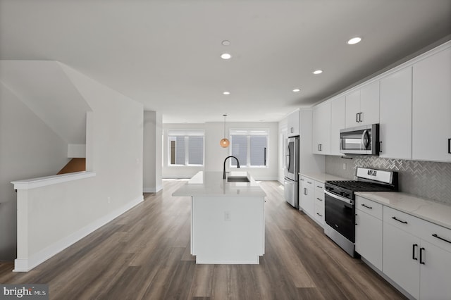 kitchen with appliances with stainless steel finishes, decorative backsplash, an island with sink, dark wood finished floors, and white cabinets
