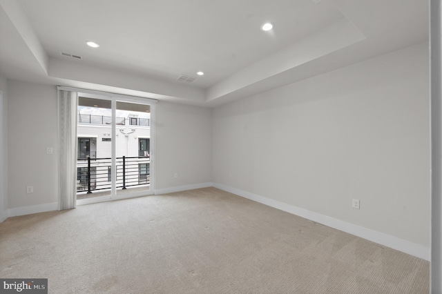 carpeted empty room featuring a raised ceiling, baseboards, and recessed lighting
