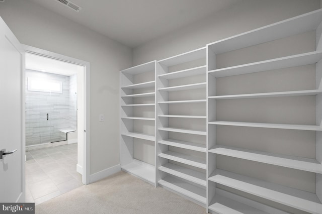 walk in closet with light tile patterned floors and light carpet