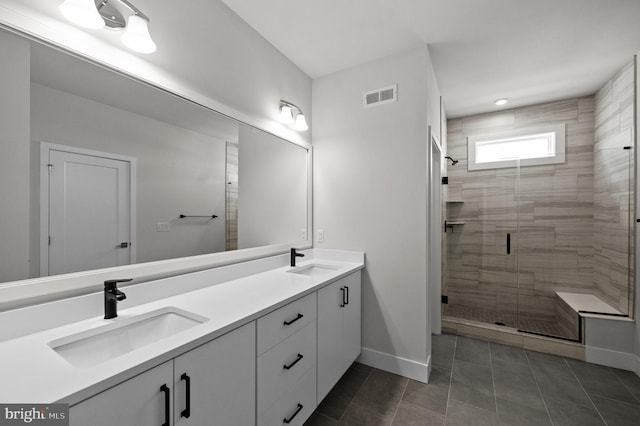 full bathroom with a stall shower, baseboards, double vanity, and tile patterned floors