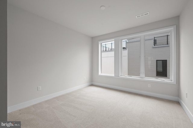 unfurnished room with light carpet and baseboards