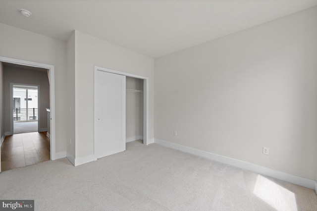 unfurnished bedroom with light carpet, baseboards, and a closet