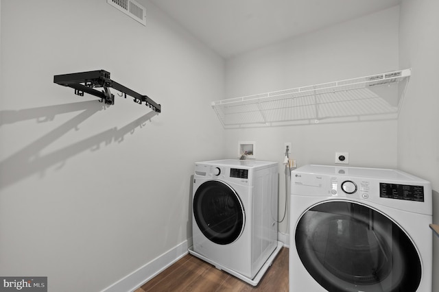 washroom featuring washer and clothes dryer, dark wood-type flooring, and baseboards