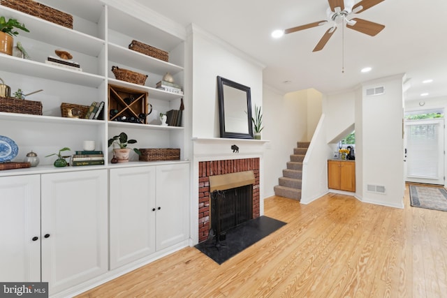 1215 Walter St SE, Washington, DC 20003 - unfurnished living room with light wood-type flooring, a brick fireplace, a ceiling fan, recessed lighting, and stairs