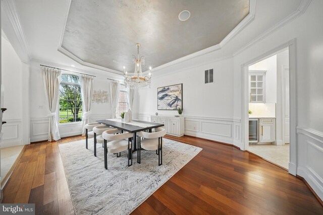 43582 Old Kinderhook Dr, Ashburn, VA 20147 - dining room featuring a raised ceiling, a decorative wall, a chandelier, wood-type flooring, and crown molding