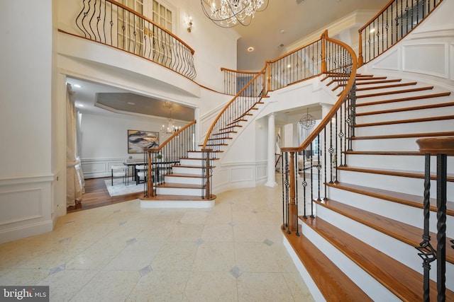 43582 Old Kinderhook Dr, Ashburn, VA 20147 - staircase featuring a chandelier, a decorative wall, a high ceiling, and a wainscoted wall