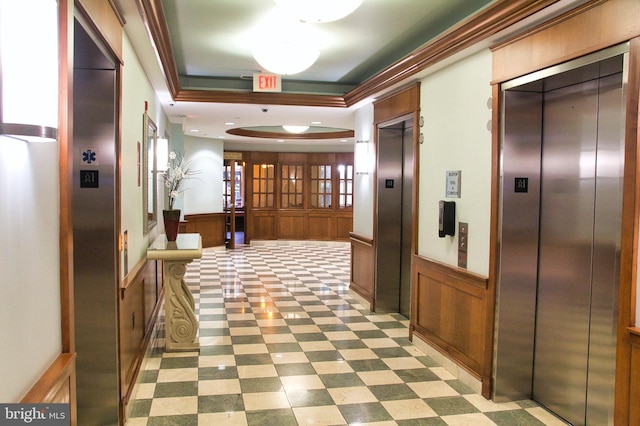 hall featuring elevator, a wainscoted wall, a tray ceiling, and tile patterned floors