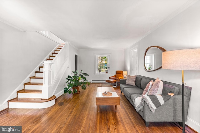 living area featuring baseboard heating, stairway, hardwood / wood-style floors, baseboards, and ornamental molding
