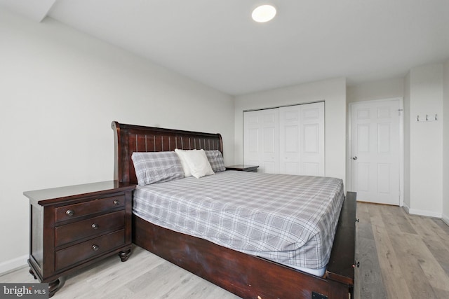 bedroom featuring light wood-type flooring, a closet, and baseboards