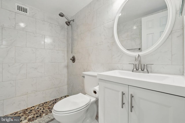 full bath featuring tile walls, toilet, tiled shower, and vanity