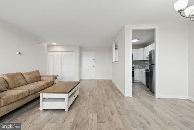 living room with light wood-type flooring, baseboards, a chandelier, and recessed lighting