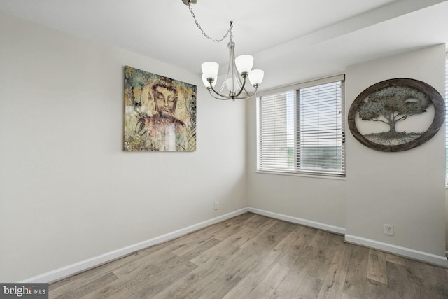 unfurnished dining area featuring a chandelier, wood finished floors, and baseboards