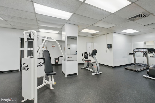 workout area featuring a drop ceiling and baseboards