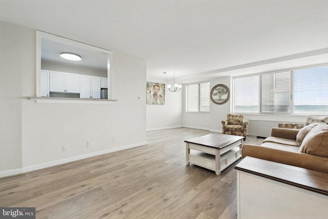 living room featuring a chandelier, light wood-style flooring, and baseboards