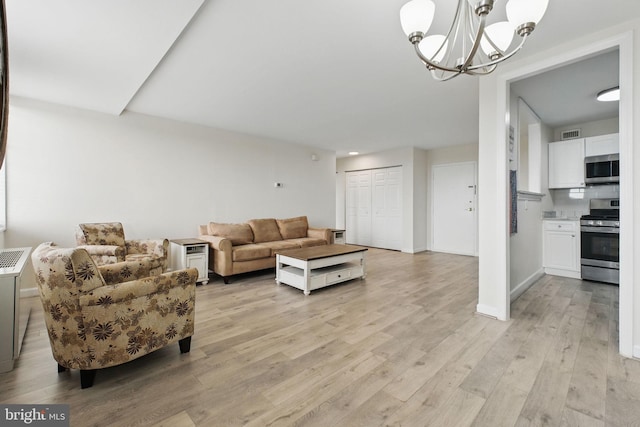 living room with light wood-style floors, a chandelier, and baseboards