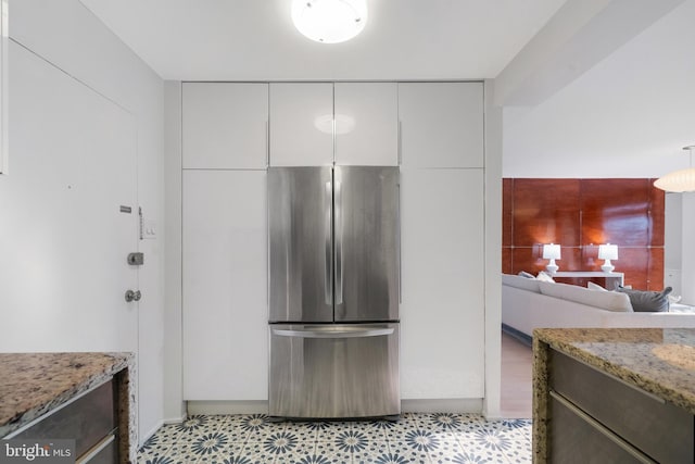 1250 4th St SW Unit W203, Washington, DC 20024 - kitchen featuring freestanding refrigerator, light stone countertops, light flooring, and white cabinetry