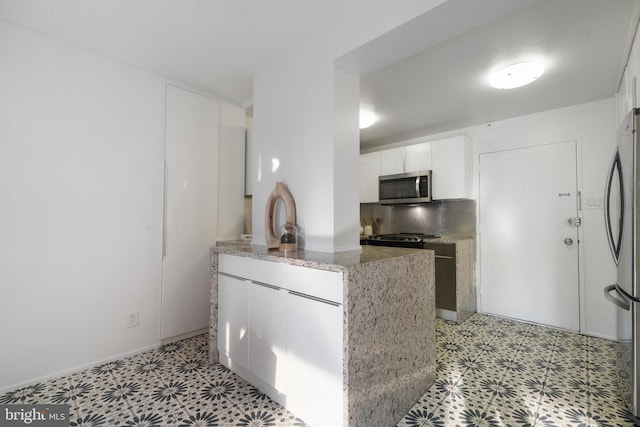 1250 4th St SW Unit W203, Washington, DC 20024 - kitchen with stainless steel appliances, a peninsula, white cabinetry, light floors, and light stone countertops