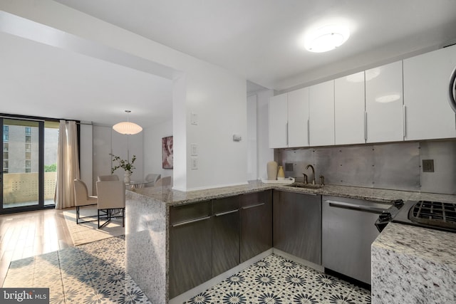 1250 4th St SW Unit W203, Washington, DC 20024 - kitchen with a peninsula, dishwasher, white cabinets, a sink, and light stone counters