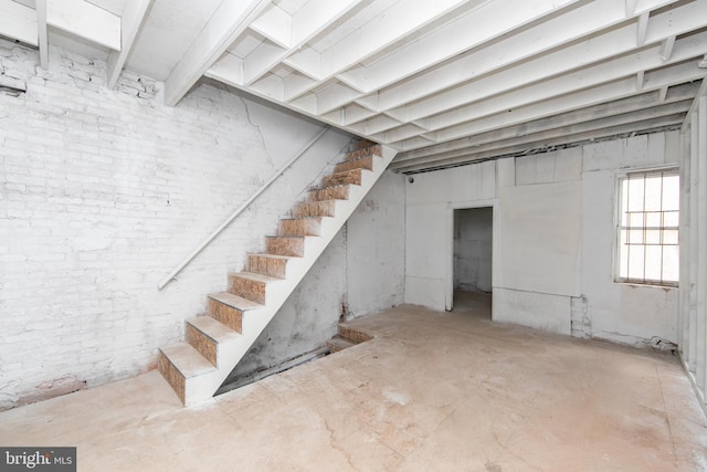 below grade area featuring stairway and brick wall