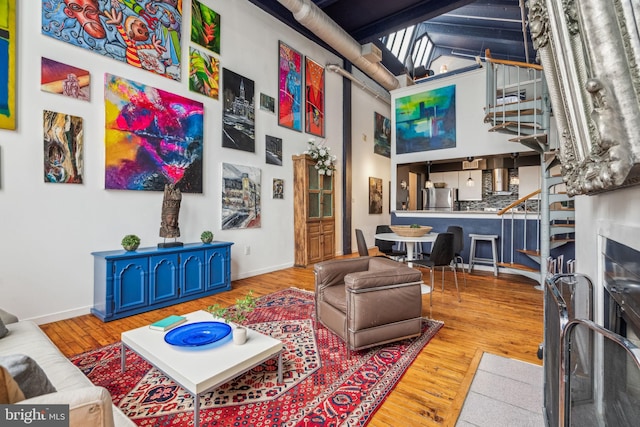 living area with wood finished floors, a towering ceiling, and baseboards