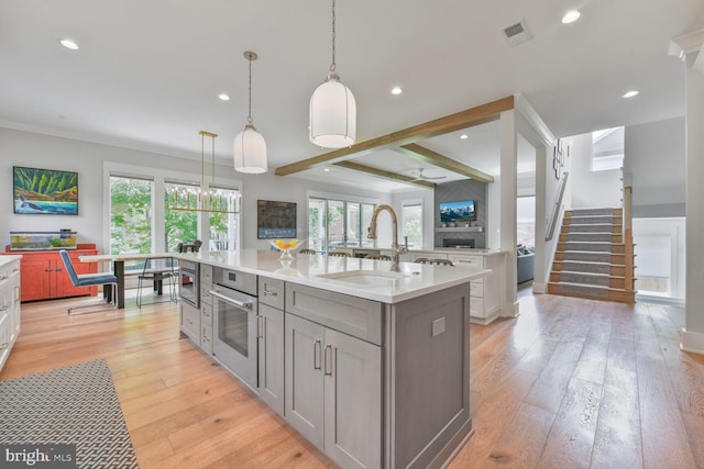 302 Jade Ct NW, Vienna, VA 22180 - kitchen featuring stainless steel oven, gray cabinetry, a center island with sink, light countertops, and a sink
