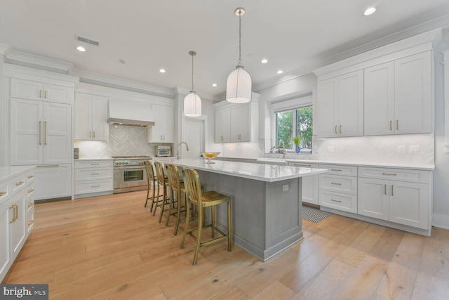 302 Jade Ct NW, Vienna, VA 22180 - kitchen with premium range hood, high end range, a breakfast bar, decorative backsplash, and light countertops