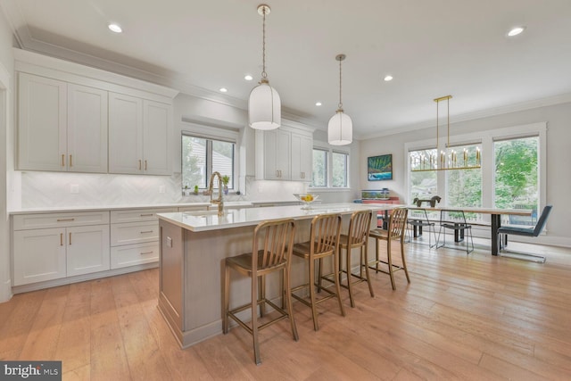 302 Jade Ct NW, Vienna, VA 22180 - kitchen featuring crown molding, an island with sink, light countertops, tasteful backsplash, and white cabinetry