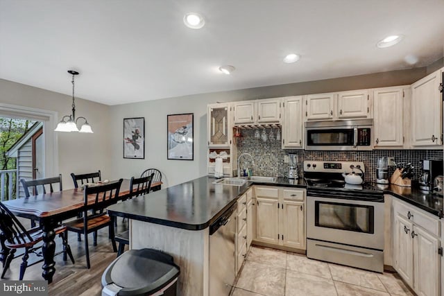 kitchen with appliances with stainless steel finishes, a sink, tasteful backsplash, dark countertops, and recessed lighting