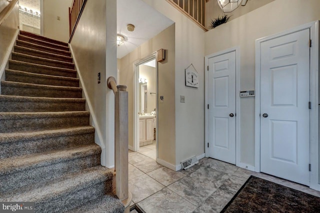 entryway with stairway, baseboards, and a towering ceiling