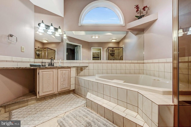 bathroom with a stall shower, a garden tub, vanity, and tile patterned floors