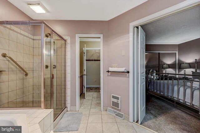 full bath featuring a stall shower, a spacious closet, tile patterned floors, and baseboards