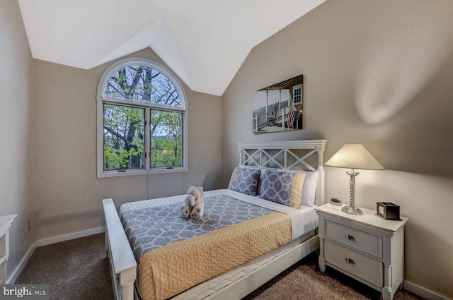 bedroom with dark colored carpet, vaulted ceiling, and baseboards