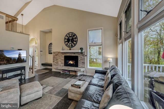 living room with high vaulted ceiling, arched walkways, a fireplace, and wood finished floors