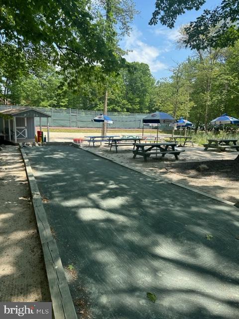 view of home's community with a game area, fence, a storage unit, an outbuilding, and view of scattered trees