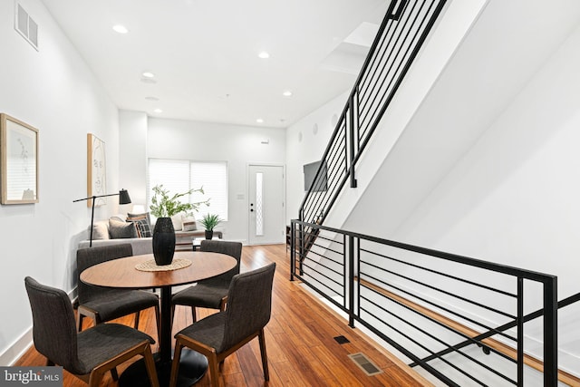 dining room featuring wood finished floors, recessed lighting, and stairs