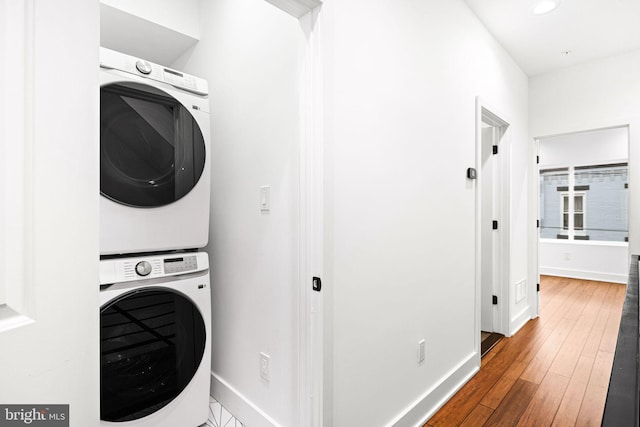 laundry room with stacked washer / drying machine, baseboards, hardwood / wood-style flooring, and recessed lighting