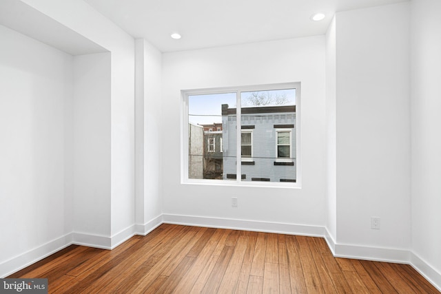 empty room featuring wood-type flooring, baseboards, and recessed lighting