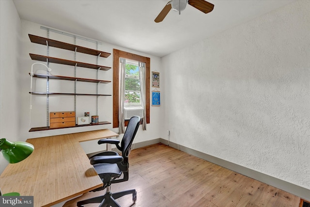 home office with wood finished floors, a ceiling fan, and a textured wall