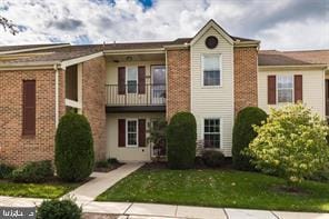 multi unit property with brick siding, a front lawn, and a balcony