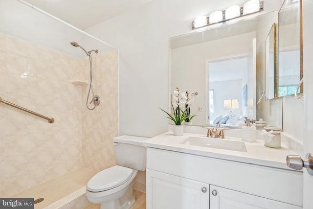 bathroom with toilet, tiled shower, and vanity