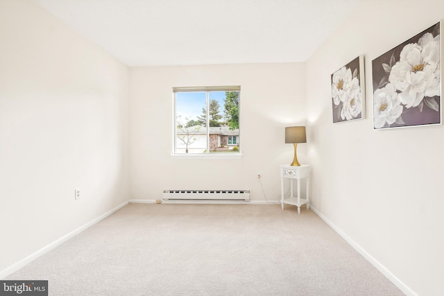 carpeted spare room featuring a baseboard heating unit and baseboards